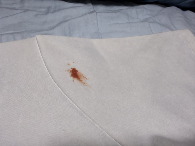 白いTシャツの左腕についたケチャップのシミをシミ取りペンで検証するイメージ画像